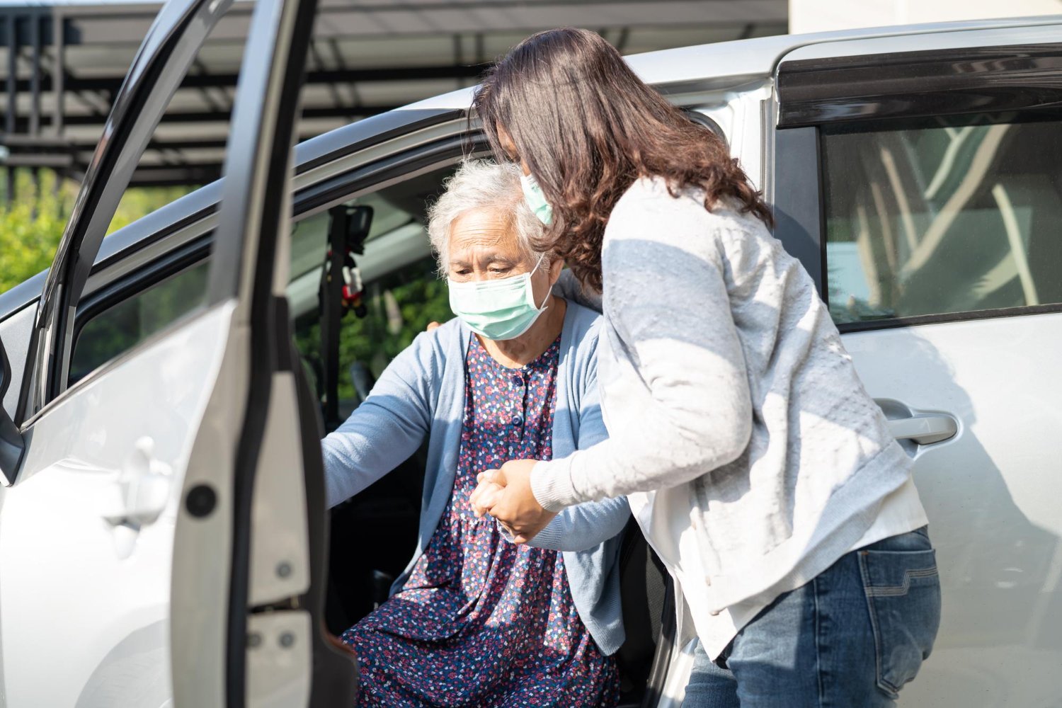 Caregiver walking alongside a client toward a waiting car
